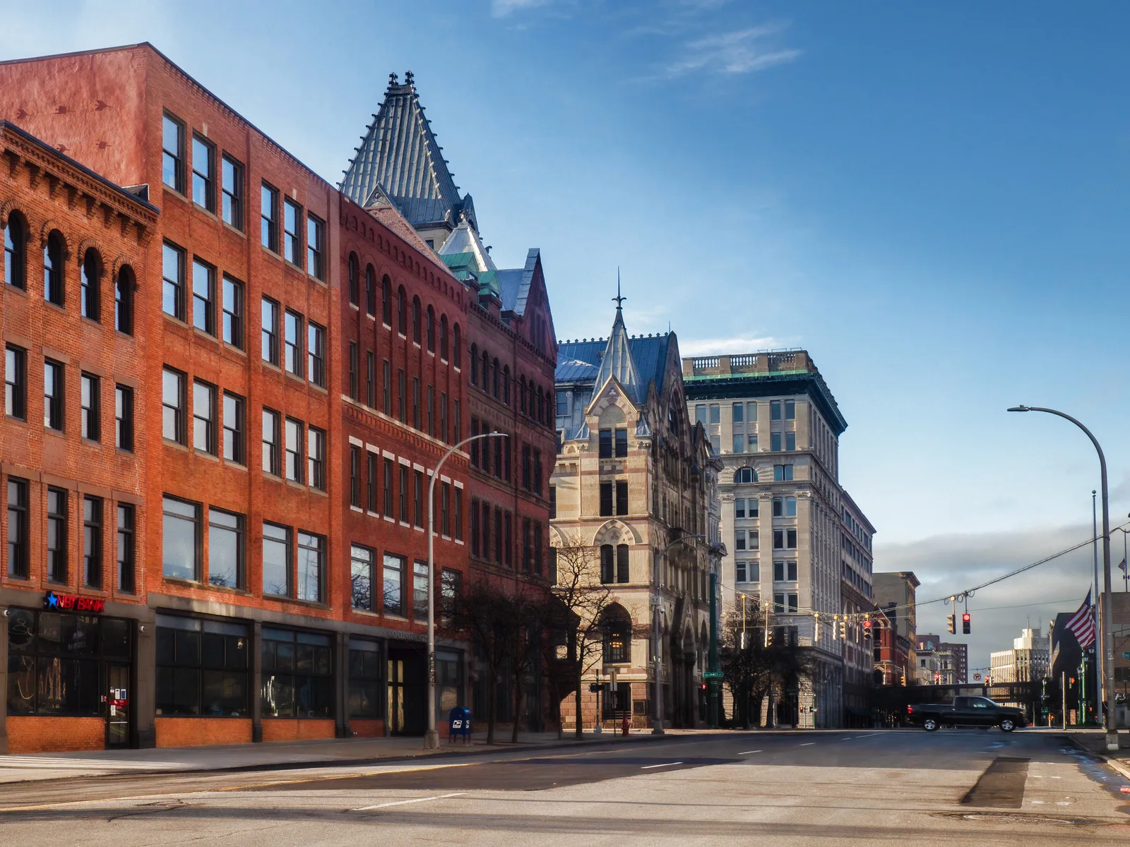 Downtown street lined with red-brick commercial buildings and an ornate Gothic-style stone building