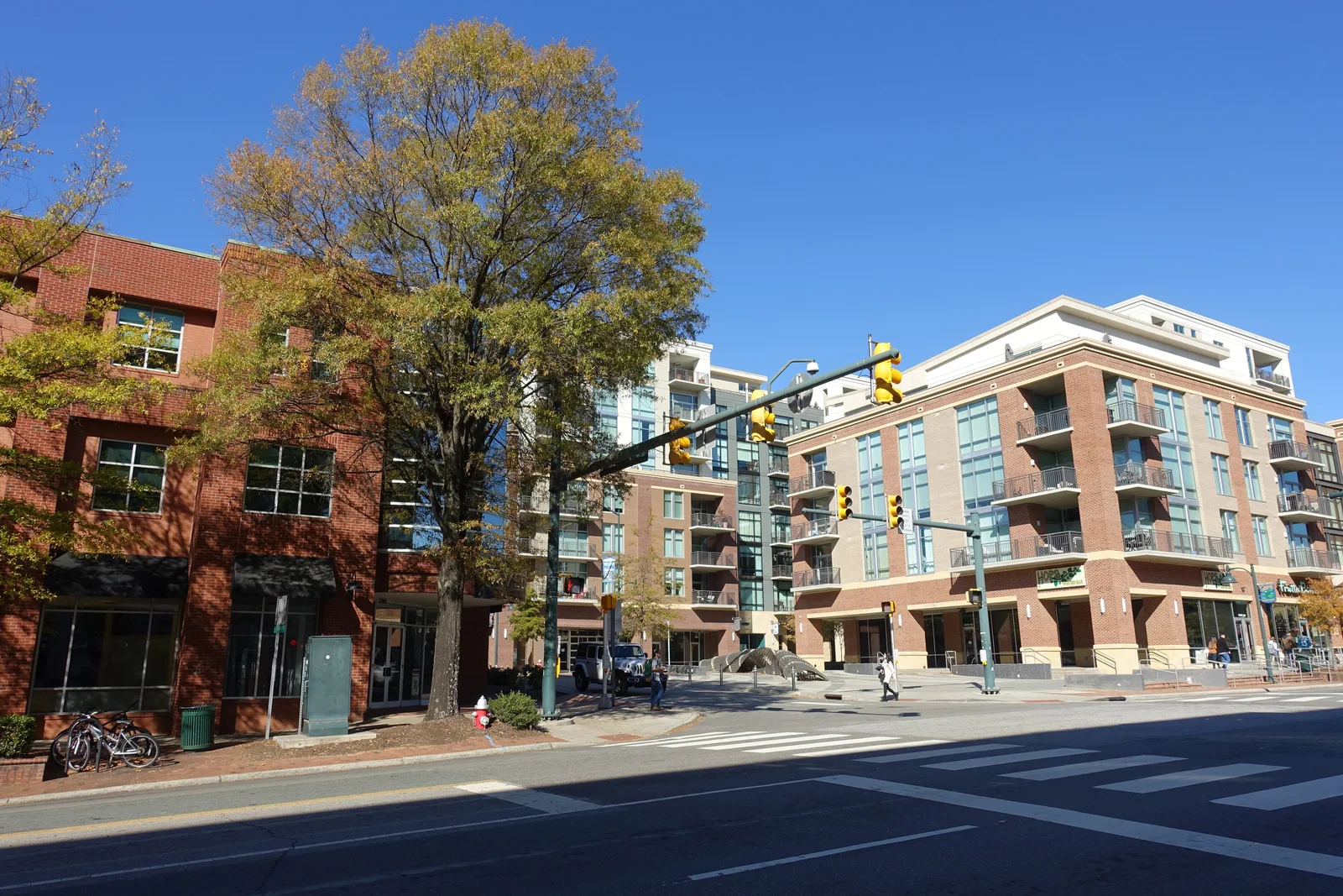 Downtown street intersection with traffic signals, crosswalk and mid-rise brick apartment and retail buildings