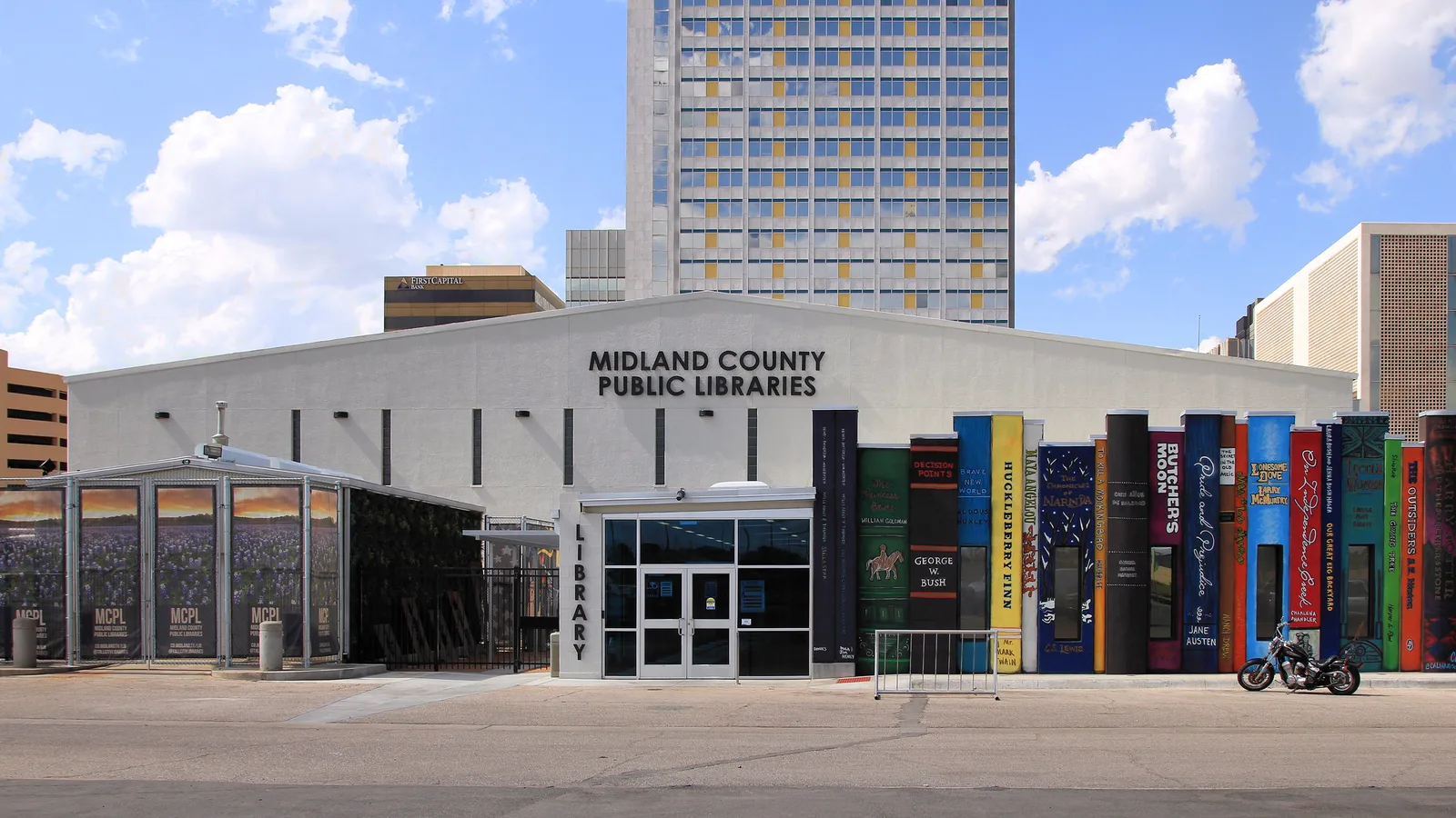 Midland County Public Libraries building with a facade painted as giant book spines, office towers behind