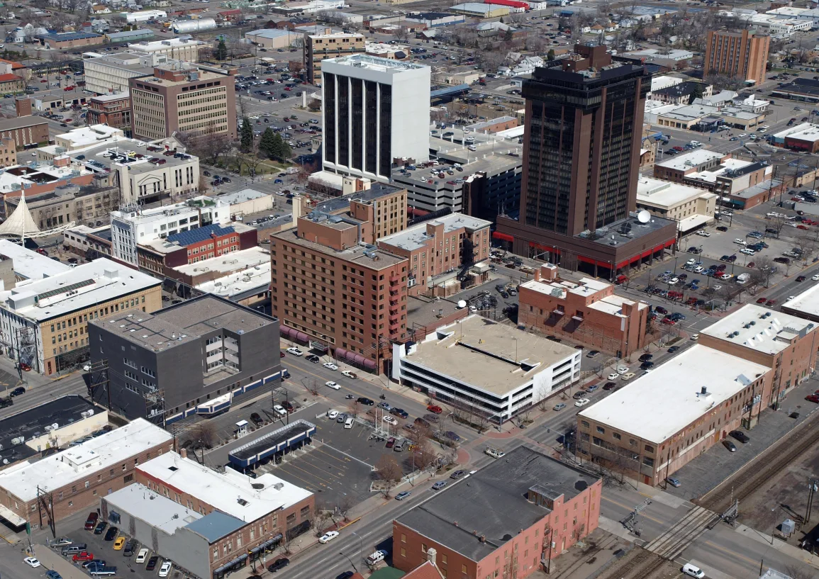 An aerial view of downtown Billings, Montana, showing a dense mix of commercial mid-rise buildings, historic brick structures, and city streets.