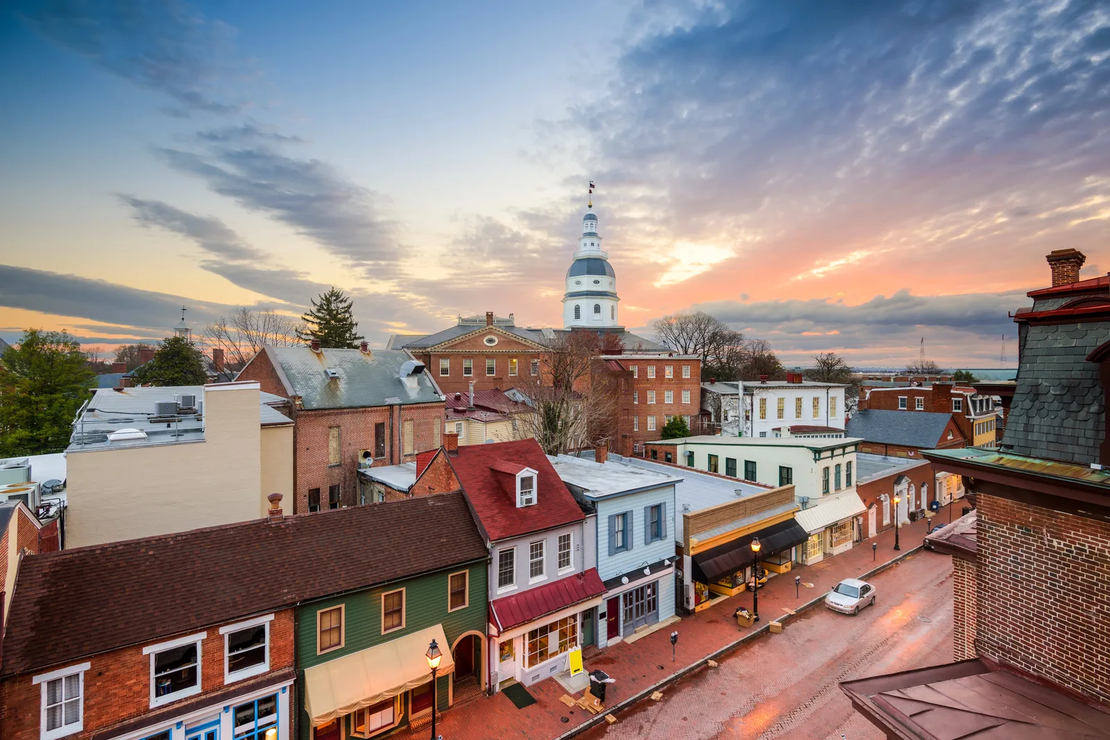 Historic brick town centre at sunset, with colourful row shops on a brick street and a white-domed building