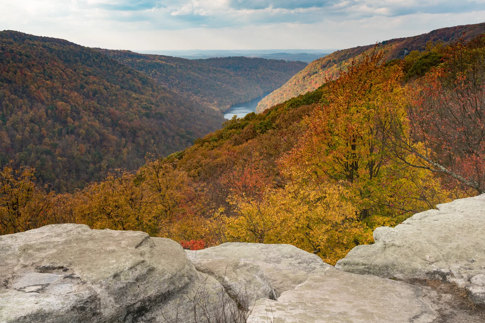 Rocky overlook above a forested river gorge in autumn, with a river winding between steep hillsides