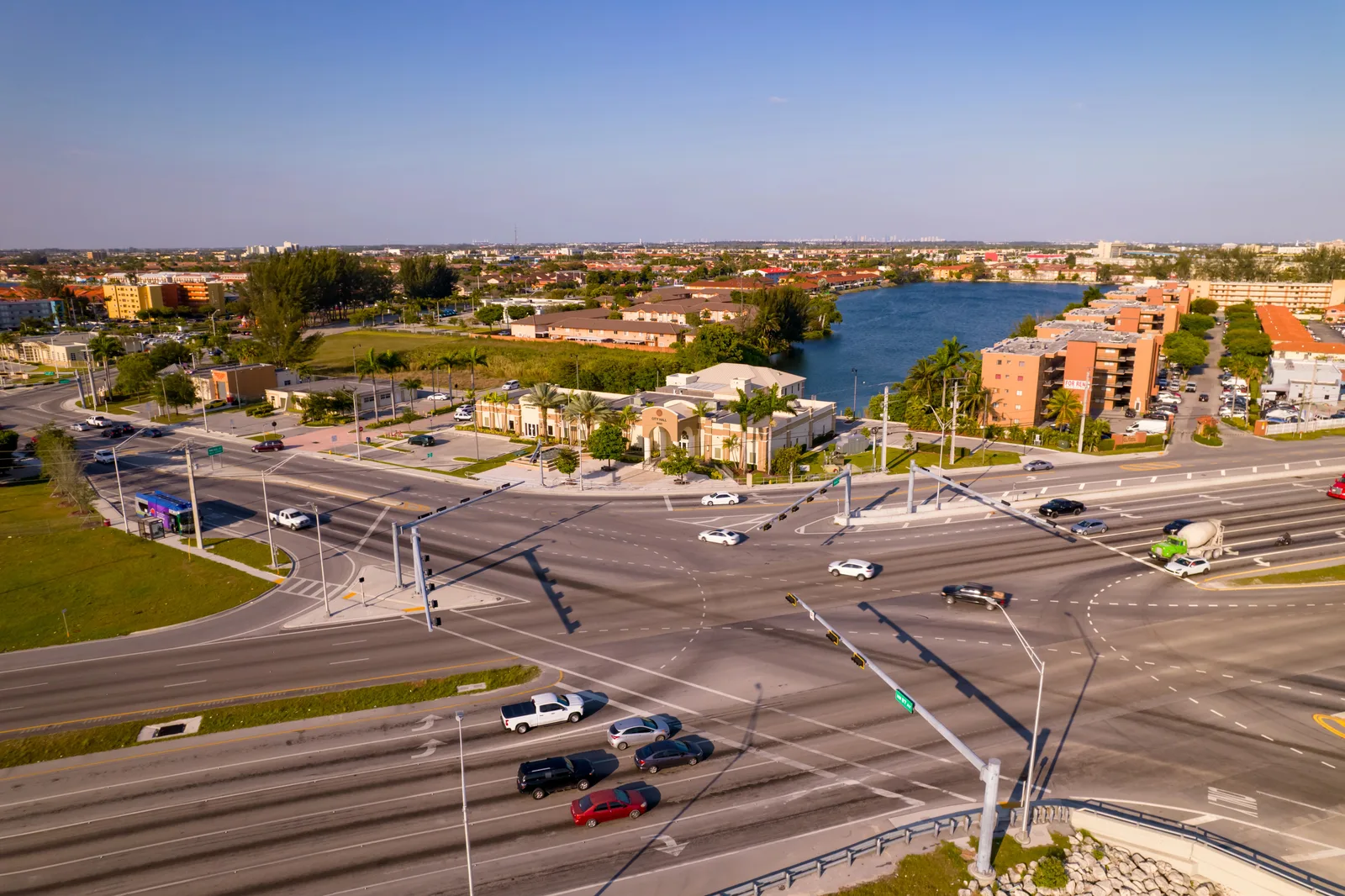 Aerial view of a busy multi-lane intersection beside a civic building, apartment blocks and a lake